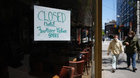 NEW YORK CITY- MAY 12:  People walk through a shuttered business district in Brooklyn on May 12, 2020 in New York City. Across America, people are reeling from the loss of jobs and incomes as unemployment soars to historical levels following the COVID-19 outbreak. While some states are beginning to re-open slowly, many business are struggling to find a profit with the news restrictions and a population that is fearful of the contagious virus.  (Photo by Spencer Platt/Getty Images)