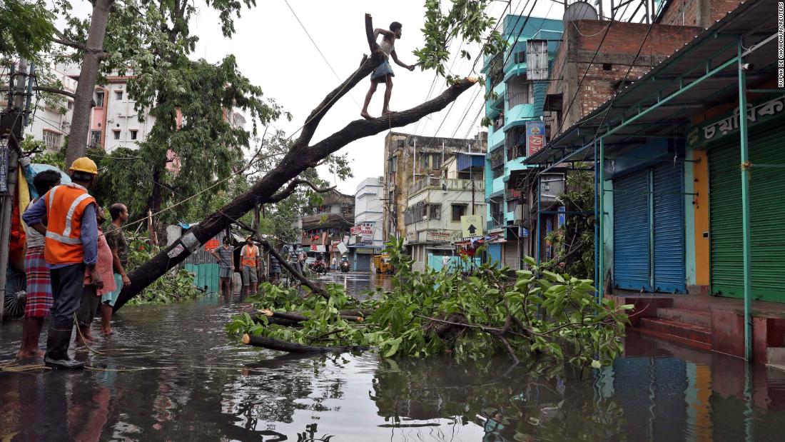 A man cuts branches from an uprooted tree in Kolkata on May 21.