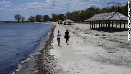 Women walk along the beach on the Long Island Sound on Tod&#39;s Point in Old Greenwich, Connecticut on May 7. 