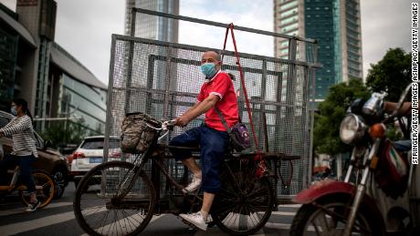 A man wearing a face mask ride tricycles to transport iron nets in Wuhan on May 11.
