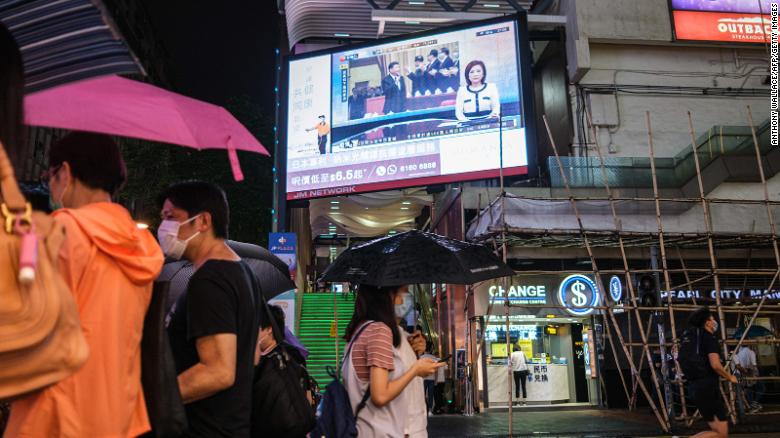 Pedestrians walk under a television screen in Hong Kong on May 21, 2020, showing a news broadcast of footage from Beijing of Chinese President Xi Jinping (C) at the Chinese People&#39;s Political Consultative Conference.