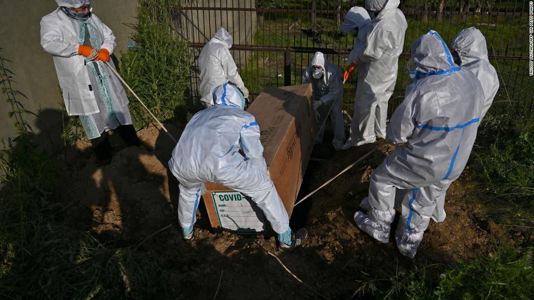 People lower the coffin of a woman who died from the coronavirus in Srinagar, India.