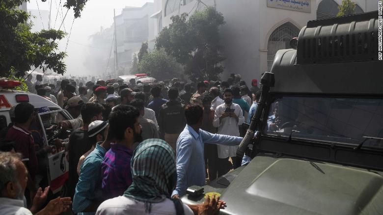 Rescue workers and bystanders gather near the site of the plane crash in Karachi on Friday.