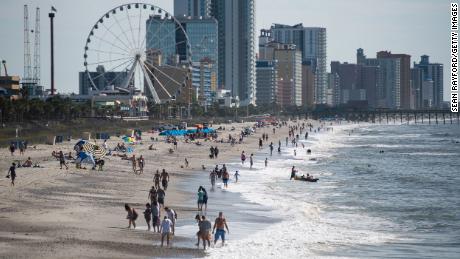 MYRTLE BEACH, SC - MAY 23: People walk and gather along the beach on the morning of May 23, 2020 in Myrtle Beach, South Carolina. Businesses, including amusements, have reopened for the Memorial Day holiday weekend after forced pandemic closures. (Photo by Sean Rayford/Getty Images)