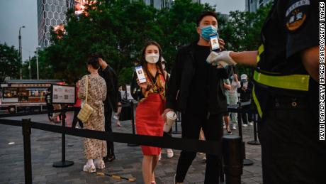  A Chinese man and woman in Beijing show their local health QR codes to a security guard as he checks her temperature before entering a shopping area on May 3.