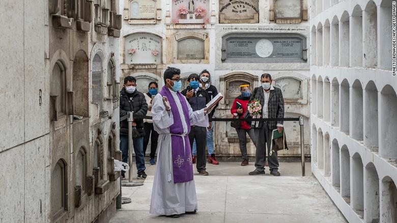 A priest conducts a ceremony after the funeral of Covid-19 victims at El Angel cemetery, in Lima on May 21.