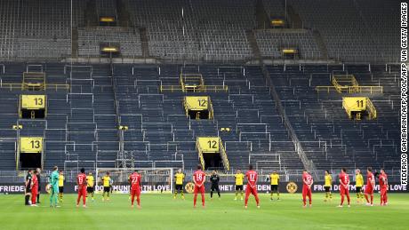 Players observe a minute of silence for the victims of the coronavirus before the German first division Bundesliga soccer match Borussia Dortmund and FC Bayern Munich.