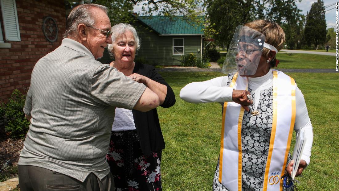 Karl Fretcher and JoAnn Payton get an elbow bump from minister Terri Foree after she married the couple in the front yard of Payton&#39;s home in Louisville, Kentucky, on May 12.
