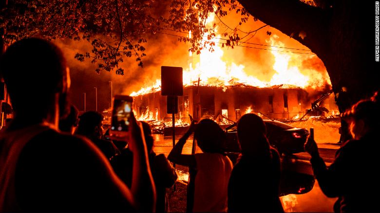 People look on as a construction site burns in a fire near the 3rd police precinct in Minneapolis, Minnesota, on Wednesday, May 27, after a night of ongoing protests in response to the death of George Floyd.