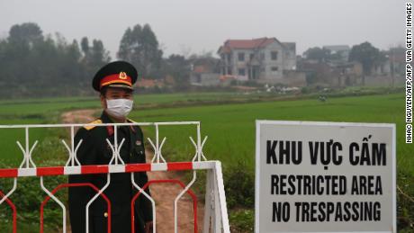 A Vietnamese People&#39;s Army officer stands next to a sign warning about the lockdown on the Son Loi commune in Vinh Phuc province on February 20.