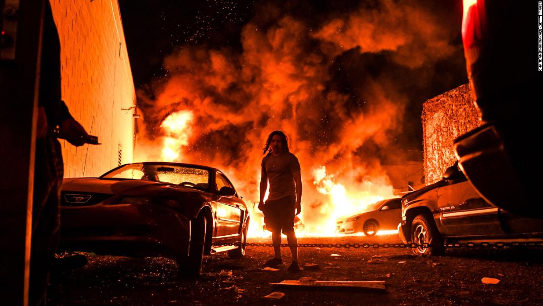 A man walks away as a car burns in a Minneapolis parking garage on May 29.