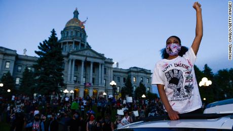 A woman wearing a mask protests near the Colorado state capitol in Denver.