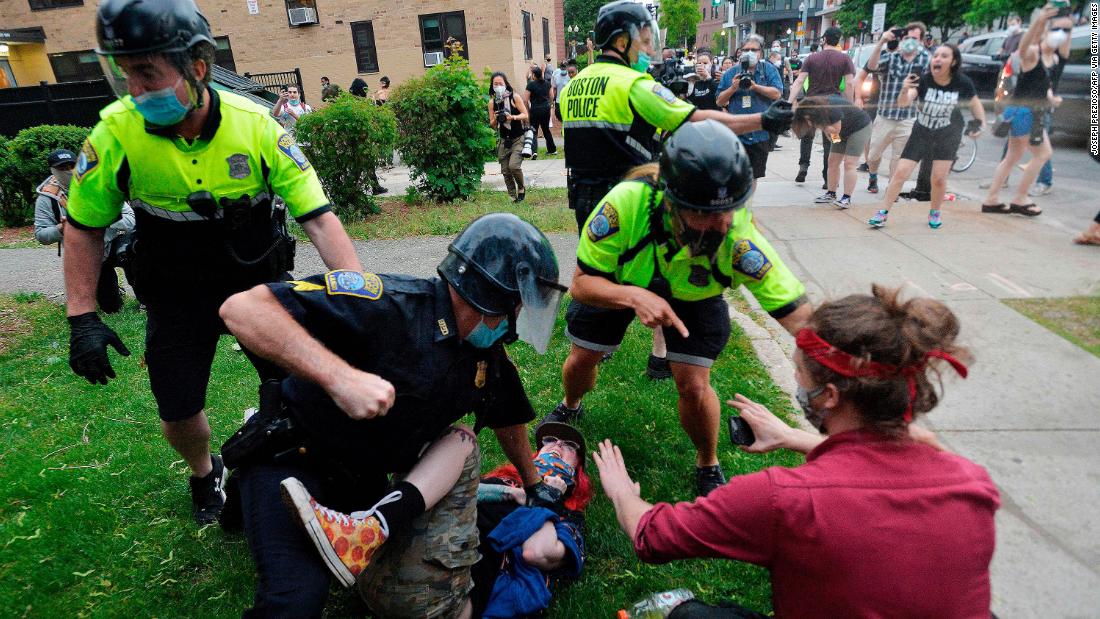 A police officer in Boston holds down a protester while another officer uses pepper spray on May 29.