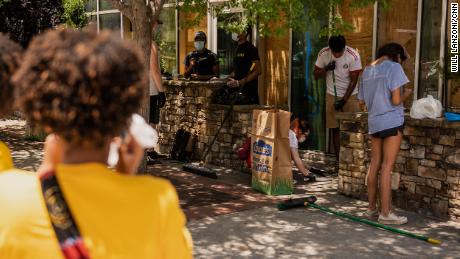 People clean up broken glass and debris outside a downtown Atlanta restaurant on Saturday, May 30. The building was vandalized during  protests.