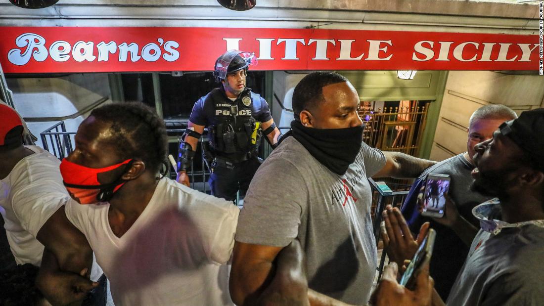 Protesters link arms and surround a police officer to protect him from the crowd in Louisville on May 28.
