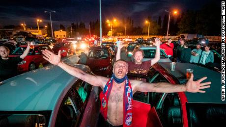 Fans cheer as they watch the Czech first division football match between FC Viktoria Plzen and AC Sparta Praha at a drive-in movie theater in Plzen, Czech Republic.