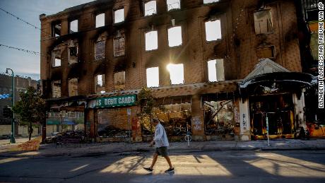 A man walks past a damaged building following overnight protests over the death of George Floyd, Sunday, May 31, 2020, in Minneapolis. 