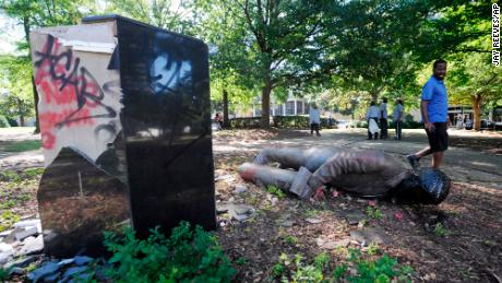 An unidentified man walks past a toppled statue of Charles Linn, a city founder who was in the Confederate Navy, in Birmingham, Ala., on Monday, June 1, 2020, following a night of unrest.