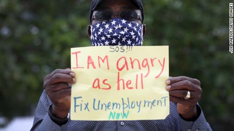 MIAMI BEACH, FLORIDA - MAY 22: Odirus Charles holds a sign that reads, &#39; I Am angry as hell Fix Unemployment Now,&#39; as he joins others in a protest on May 22, 2020 in Miami Beach, Florida. Unemployed hospitality and service workers who have not received unemployment checks held the protest demanding Florida Governor Ron DeSantis fix the unemployment system and send out their benefits. Since the closure of all non-essential businesses due to the coronavirus pandemic, hundreds of thousands of hospitality workers across Florida find themselves out of work. Florida&#39;s unemployment system has not worked reliably. (Photo by Joe Raedle/Getty Images)