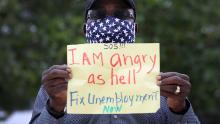 MIAMI BEACH, FLORIDA - MAY 22: Odirus Charles holds a sign that reads, ' I Am angry as hell Fix Unemployment Now,' as he joins others in a protest on May 22, 2020 in Miami Beach, Florida. Unemployed hospitality and service workers who have not received unemployment checks held the protest demanding Florida Governor Ron DeSantis fix the unemployment system and send out their benefits. Since the closure of all non-essential businesses due to the coronavirus pandemic, hundreds of thousands of hospitality workers across Florida find themselves out of work. Florida's unemployment system has not worked reliably. (Photo by Joe Raedle/Getty Images)