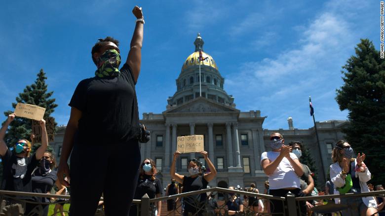 A woman at the state Capitol in Denver raises her fist during the fifth consecutive day of protests.