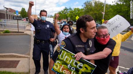 A protester and police officer walk in an embrace during a demonstration march in Connecticut.