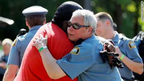 A protester and officer share an embrace. 