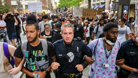 Denver Police Chief Paul Pazen links arms with people protesting.