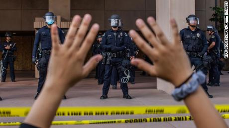 A demonstrator holds her hands up while she kneels in front of the Police in Anaheim, California, during a peaceful protest of George Floyd&#39;s killing.