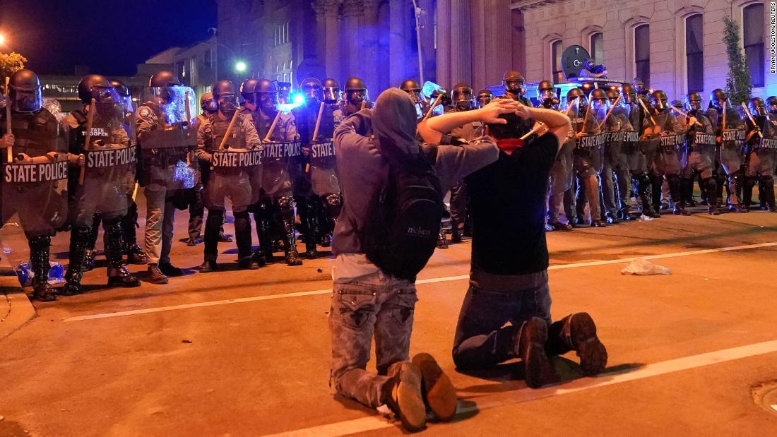 Two men kneel in front of a line of Kentucky state troopers during a protest in Louisville on June 1.