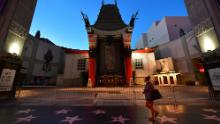 A woman walks past the closed courtyard in front of the TCL Chinese Theater, famed for the hand and foot prints of movie stars.