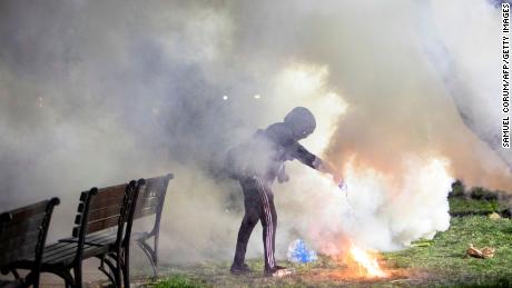 A demonstrator pours water on a tear gas canister in front of the White House on May 31, 2020. - Police fired tear gas outside the White House late Sunday as major US cities were put under curfew to suppress rioting as anti-racism protestors again took to the streets to voice fury at police brutality. 