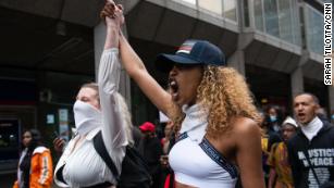 Two protesters join hands as they rally in London.