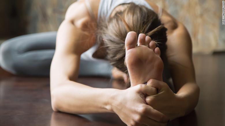 Incorporating a wellness routine into your schedule can help you weather the uncertainty of the times we live in. Here, a woman practicing yoga does a head-to-knee forward bend, or Janu Sirsasana pose.