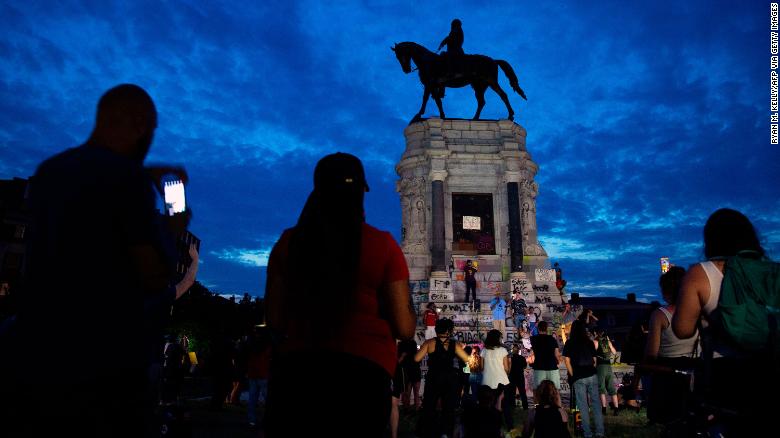 People gather around the Robert E. Lee statue in Richmond, Virginia, on June 4, calling for its removal. CNN has blurred expletives written on the base of the statue. 