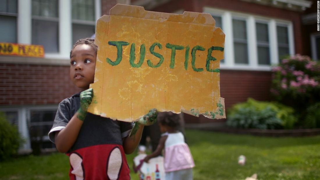 Xavier Brown shows his support as demonstrators march past his home in St. Paul, Minnesota, on June 6.