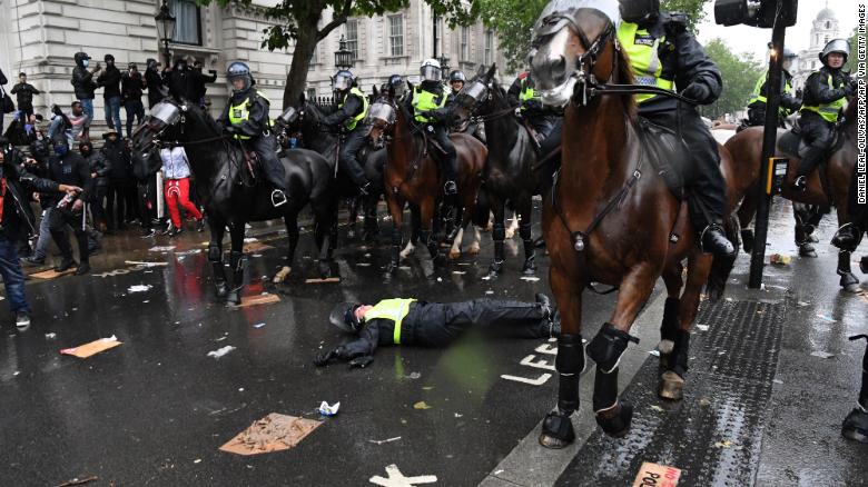 A mounted police officer lays on the road after her horse bolted.