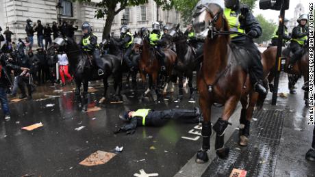 A mounted police officer lays on the road after her horse bolted.