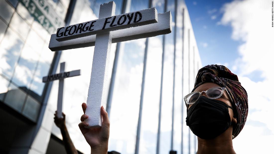 A protester wearing a mask holds a cross with the name of George Floyd during a protest at Avenida Presidente Vargas on June 7, in Rio de Janeiro, Brazil. 