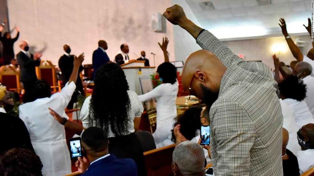 Mourners pray as they hold up their arms during the service in Raeford.