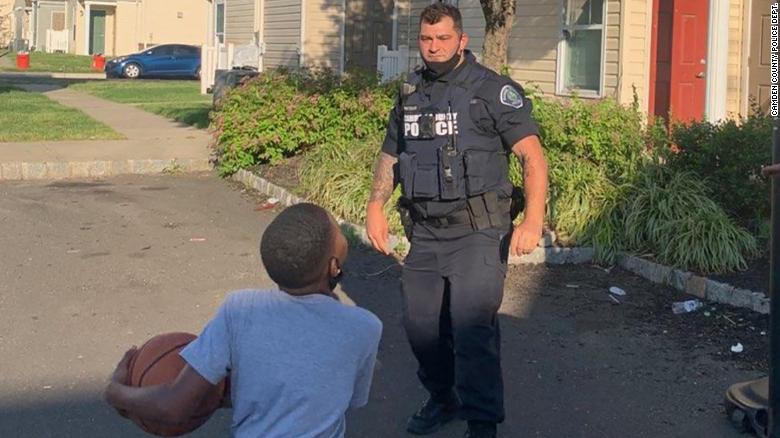 A Camden County officer plays basketball with a young resident.