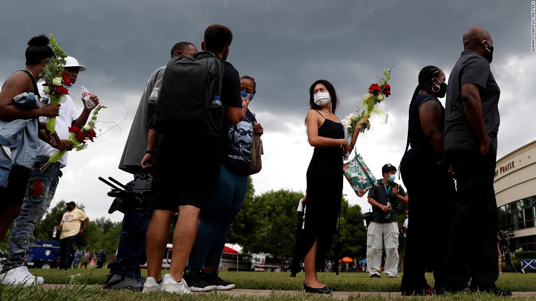 A woman holds flowers as she waits in line in Houston.