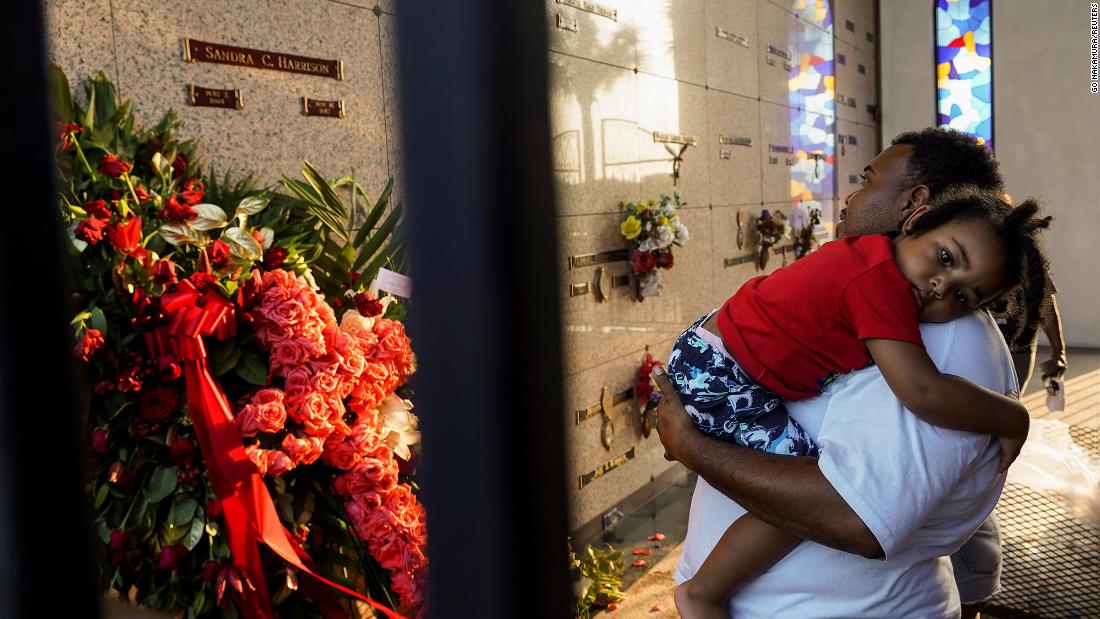 A man carries a child while paying respects at Houston Memorial Gardens in Pearland, Texas, Floyd&#39;s final resting place.