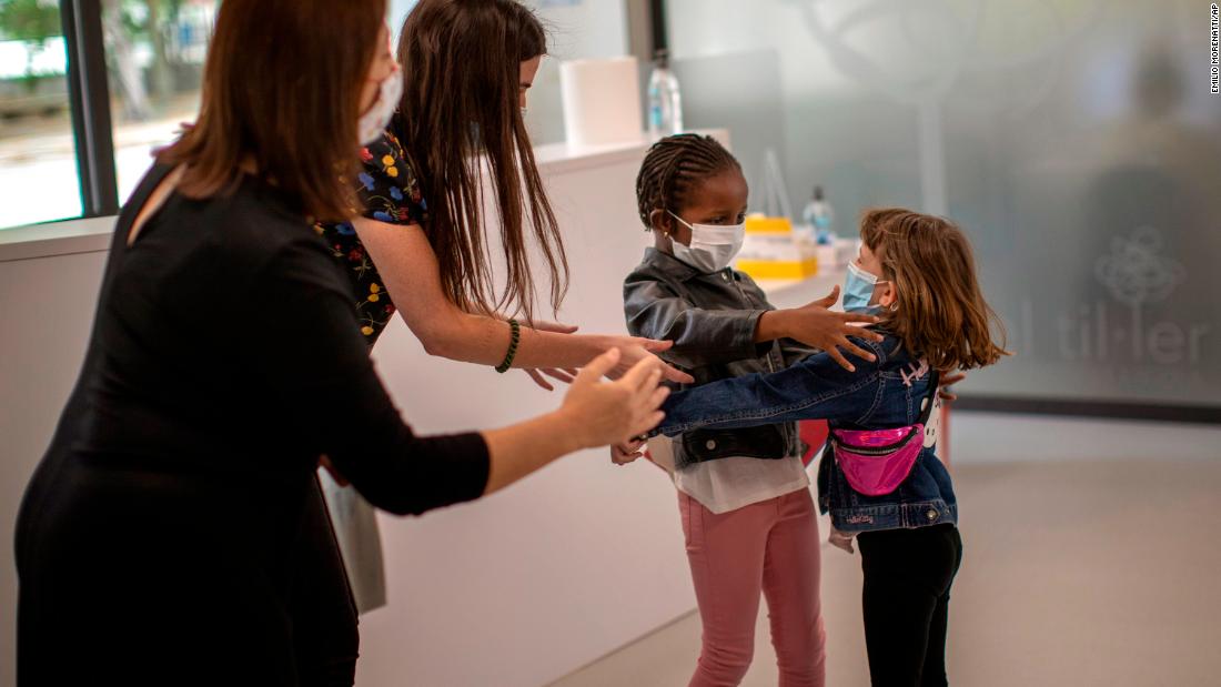 Teachers in Barcelona, Spain, try to prevent a hug between 6-year-olds Wendy Otin and Oumou Salam Niang as they meet on the first day of school following a lockdown.