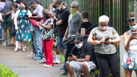 Steven Posey checks his phone as he waits in line to vote, Tuesday, June 9, 2020, at Central Park in Atlanta. Voters reported wait times of three hours. 