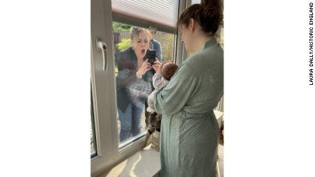 A woman meets her grandchild for the first time through a closed window during lockdown in Liverpool, England