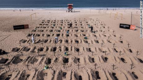 Activists from the Brazilian NGO Rio de Paz dig mock graves on Copacabana beach.