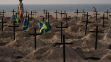 A woman walks amid symbolic graves on Rio de Janeiro&#39;s Copacabana beach. They were dug by activists protesting the government&#39;s handling of the Covid-19 pandemic.