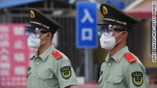 Paramilitary police officers wear face masks and goggles as they stand guard at an entrance to the closed Xinfadi market in Beijing on June 13.