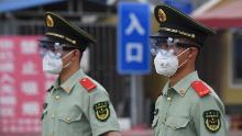 Polițiștii paramilitari poartă măști și ochelari în timp ce stau de pază la intrarea pe piața închisă a Xinfadi din Beijing, pe 13 iunie.